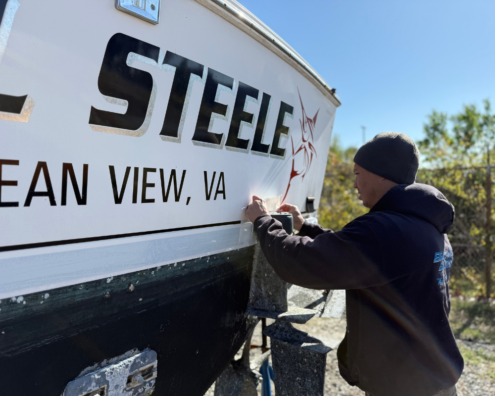 man painting side of boat